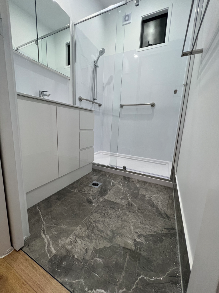 Homelife Pods bathroom interior shot with dolomite porcelain tiles, white cabinetry and shower with disability aids